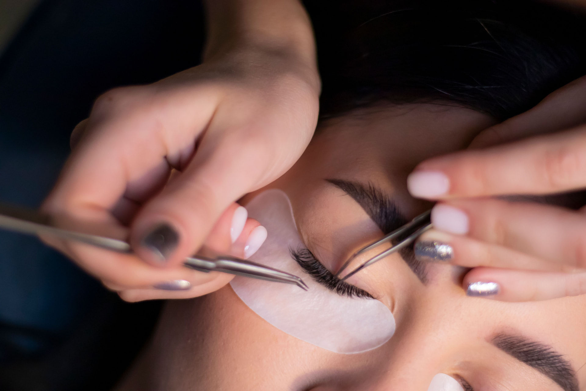 Close-up of a lash artist applying eyelash extensions