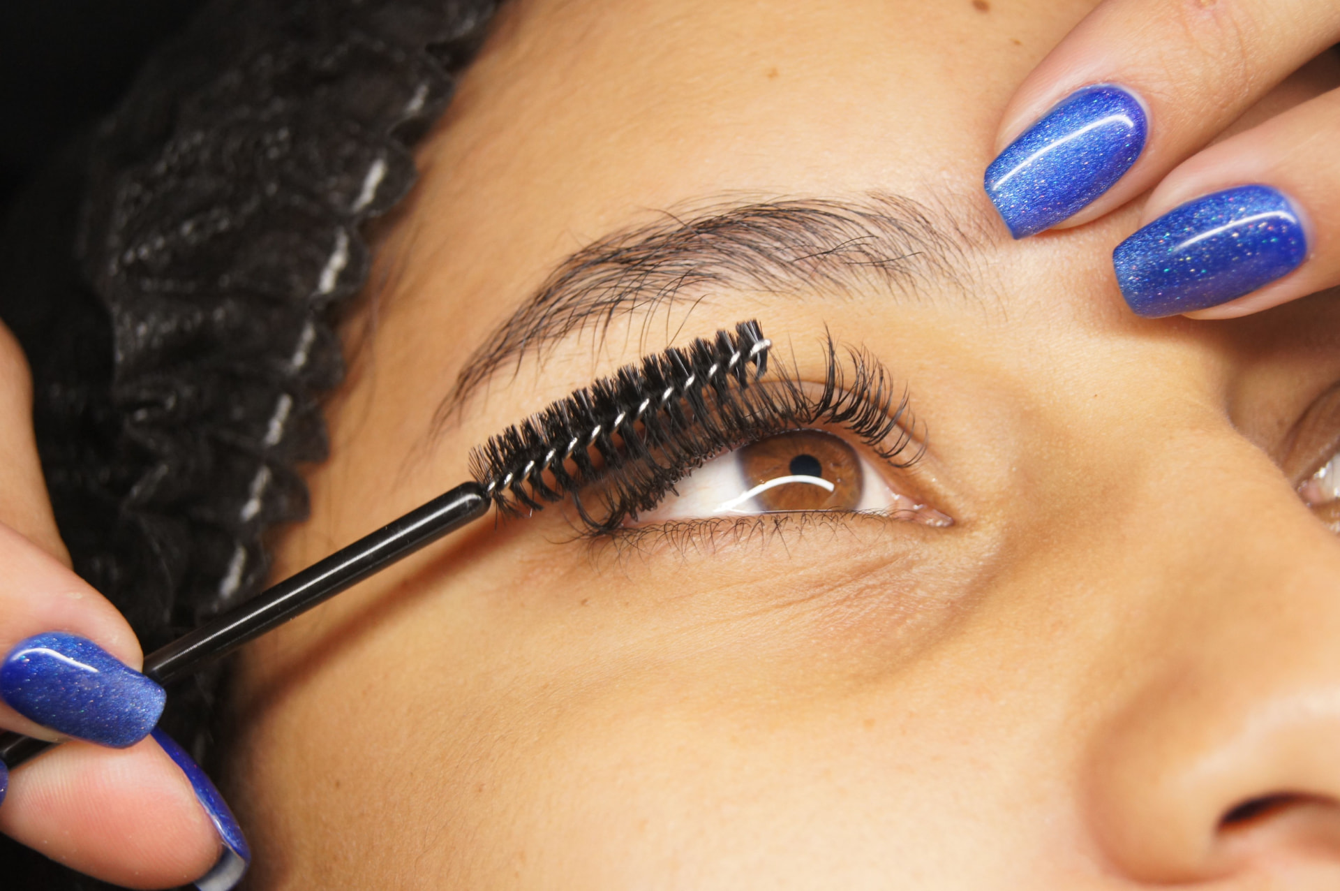 Close-up of a lash artist brushing finished lash extensions